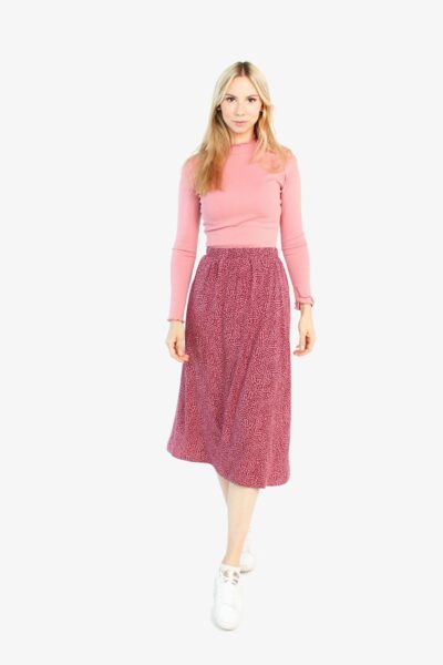 Das Model trägt einen Midirock in bordeaux rosé von LA.LUKA Berlin. Der High-Waist-Rock mit Gummizug geht bis zur Mitte der Wade. Der Rock ist bordeaux mit rosé farbenen Pünktchen.