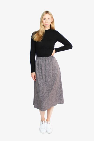 Das Model trägt einen Midirock in grau von LA.LUKA Berlin. Der High-Waist-Rock mit Gummizug geht bis zur Mitte der Wade. Der Rock ist grau mit hellgrauen Pünktchen.